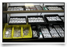 Display of various boxes and trays holding small mechanical parts or coins.